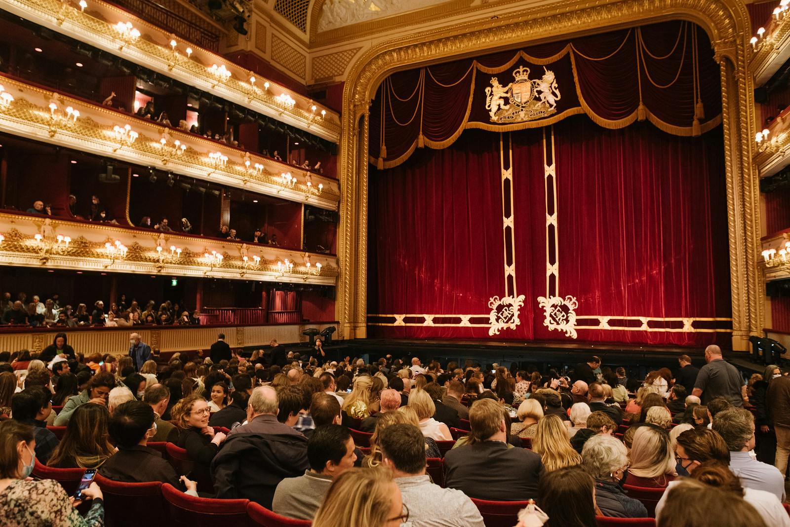 A busy crowd is seated prior to a performance of Swan Lake at the Royal Opera House in the auditorium.