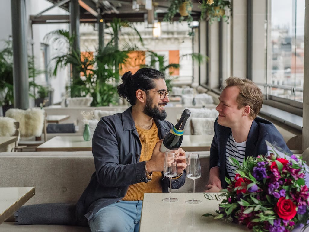 A couple smiling at each other in a rooftop restaurant.