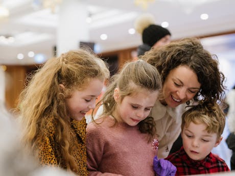 A woman with a three small children smiling at an event.